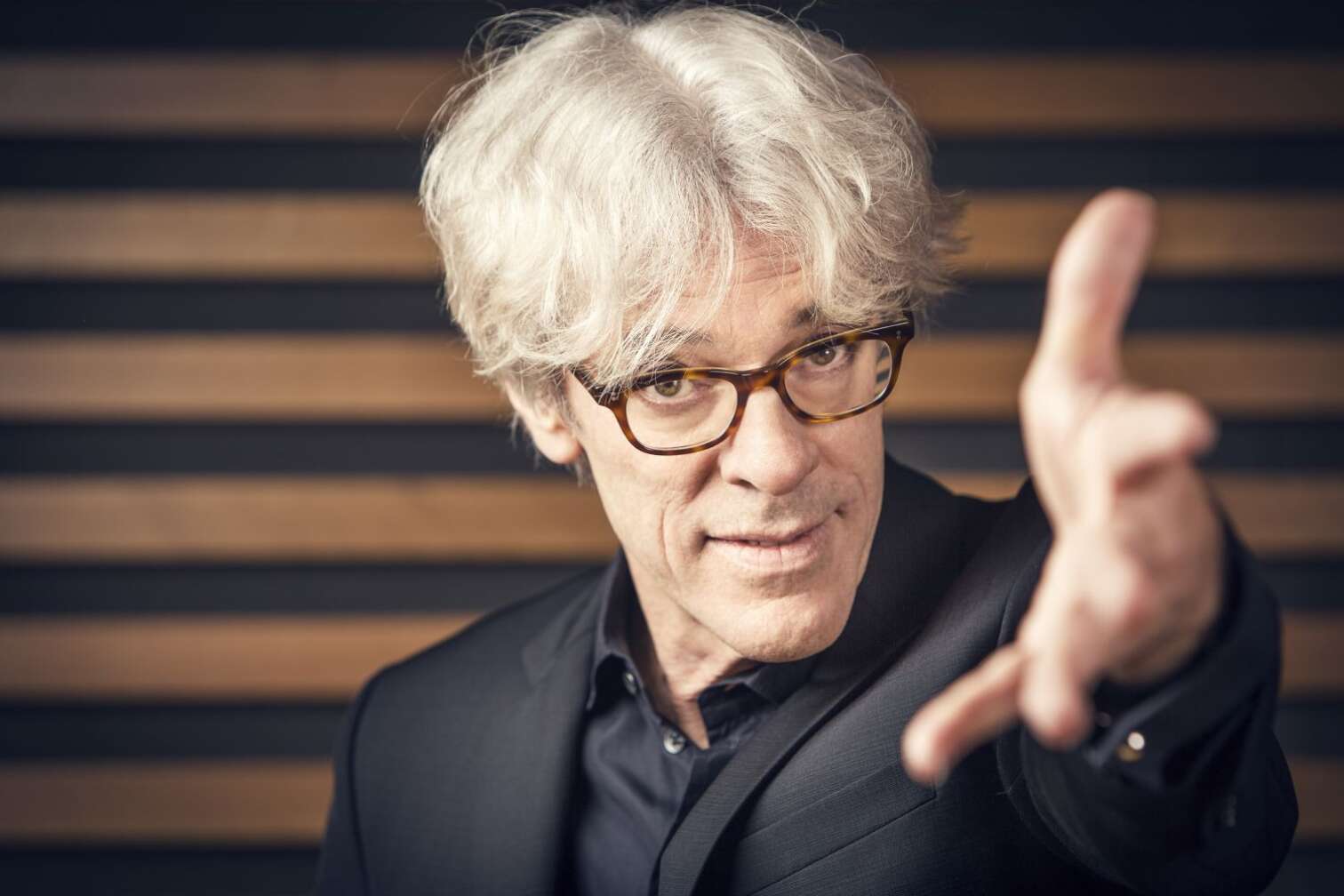 Stewart Copeland blickt herausfordernd in die Kamera und streckt die Hand der Linse entgegen