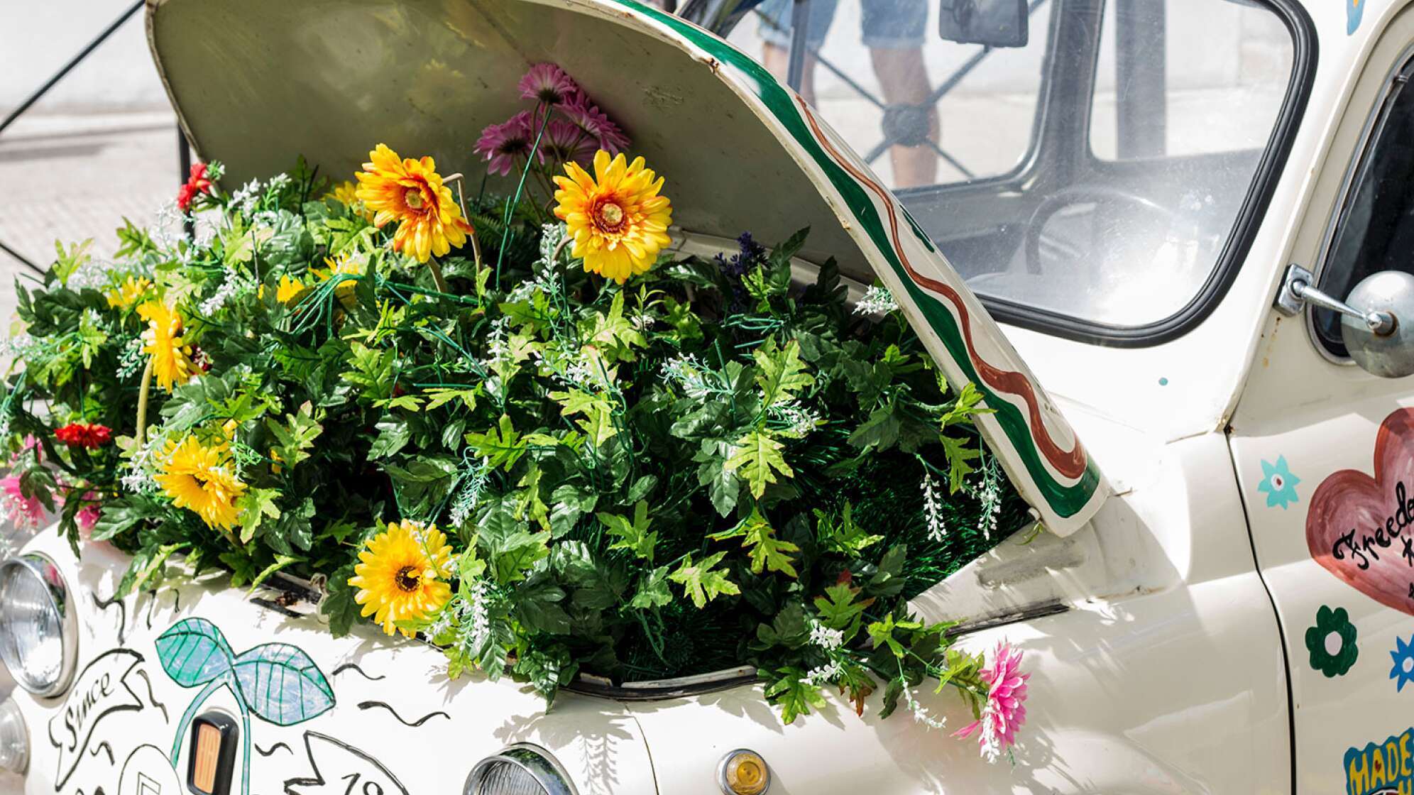 alter Fiat 500 mit Blumenkasten im Motorraum, gelbe Blüten sprießen